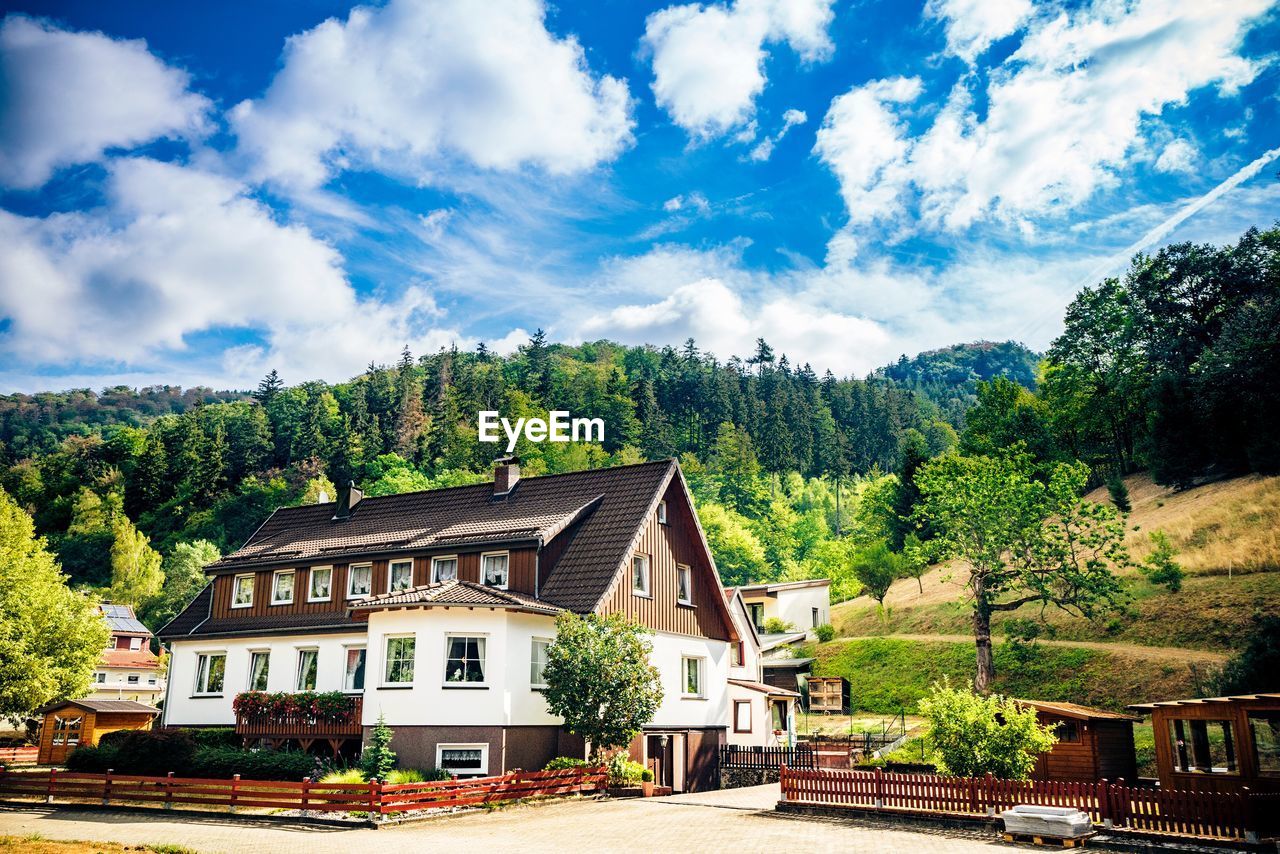 HOUSE AMIDST TREES AND PLANTS AGAINST SKY