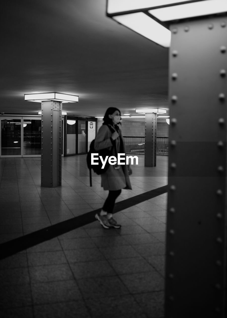 FULL LENGTH OF WOMAN WALKING IN ILLUMINATED SUBWAY