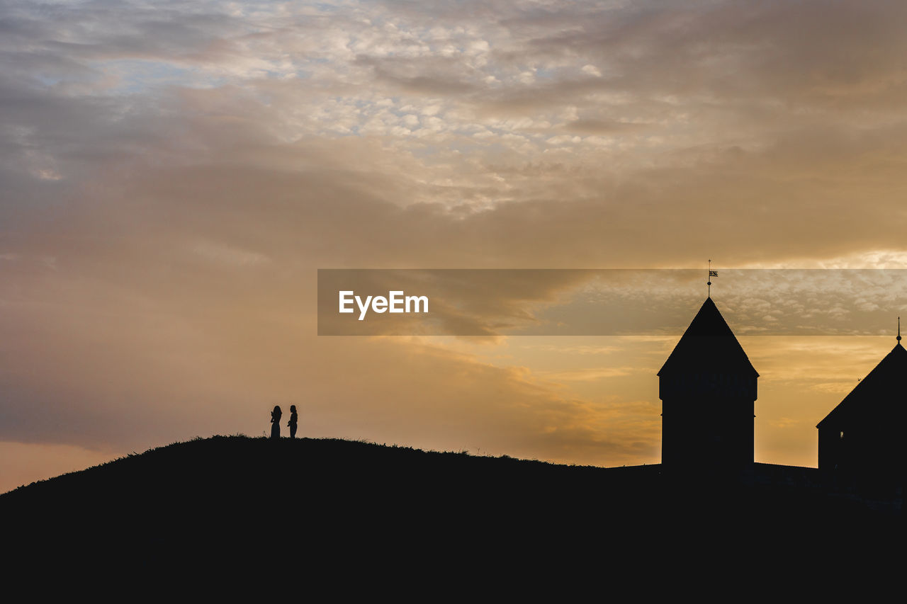 Silhouette temple against building during sunset