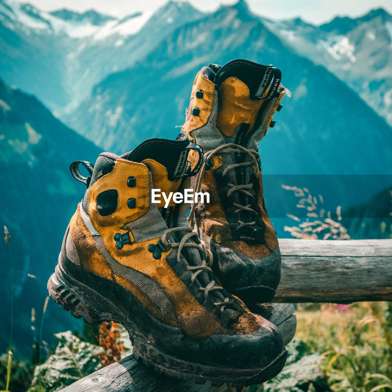 Low angle view of yellow hiking boots against mountain range view in background 