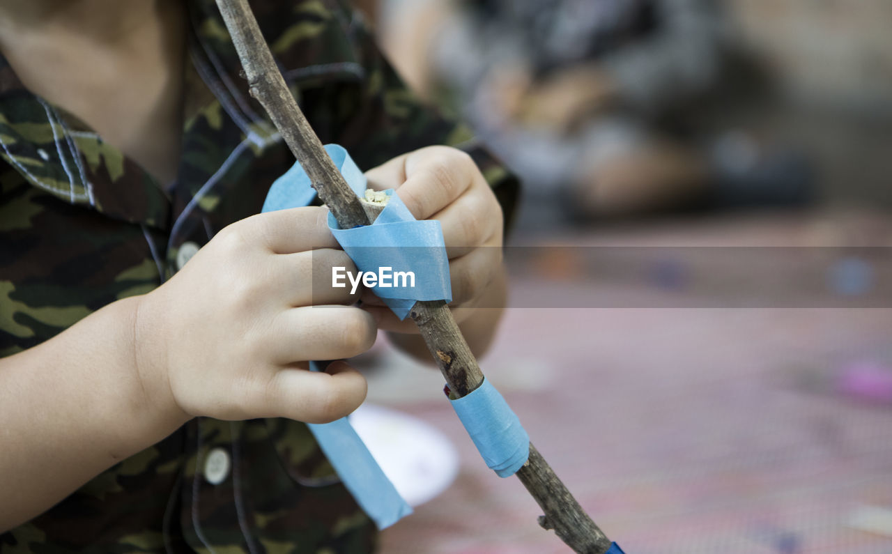 Close-up of person tying sticks with adhesive tape