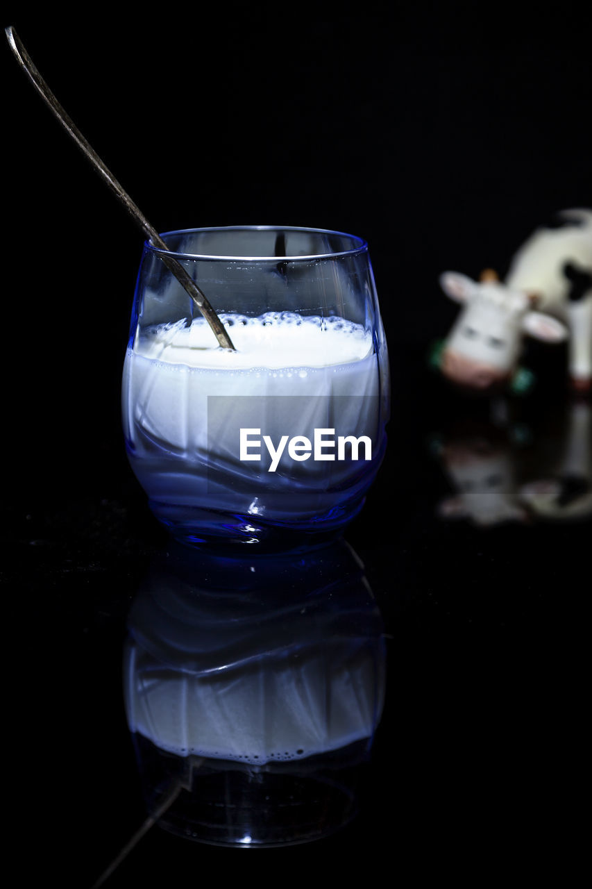 Composition of a glass of milk with a spoon on a black background