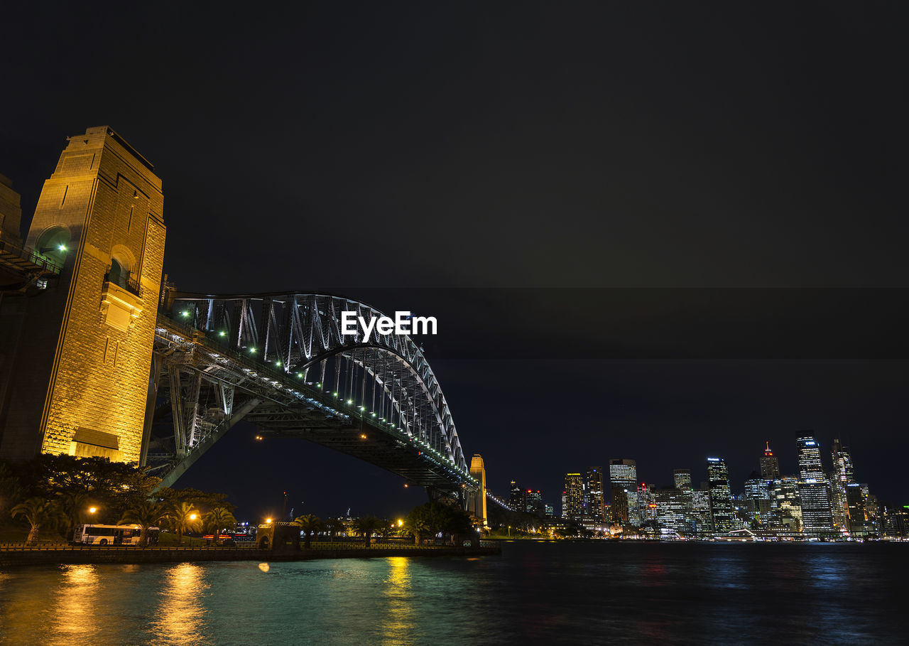 ILLUMINATED BUILDINGS BY RIVER AT NIGHT