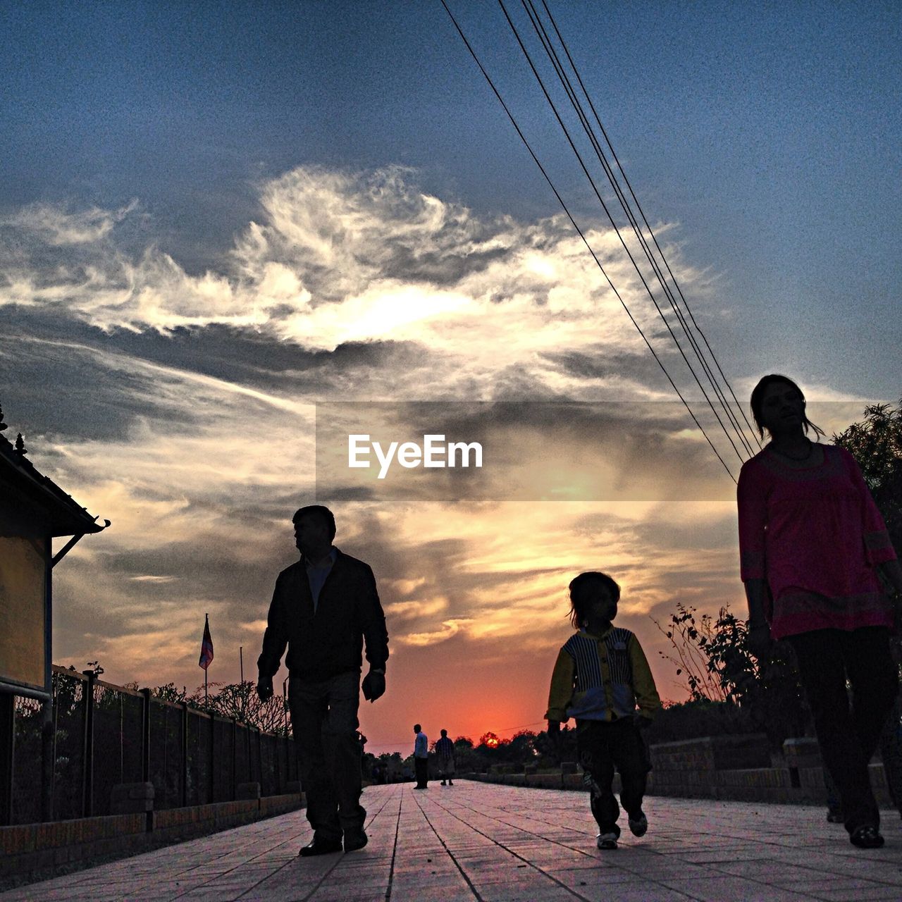 Low angle view of people walking on road against clouds