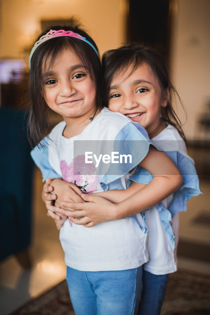 Portrait of cheerful sisters embracing