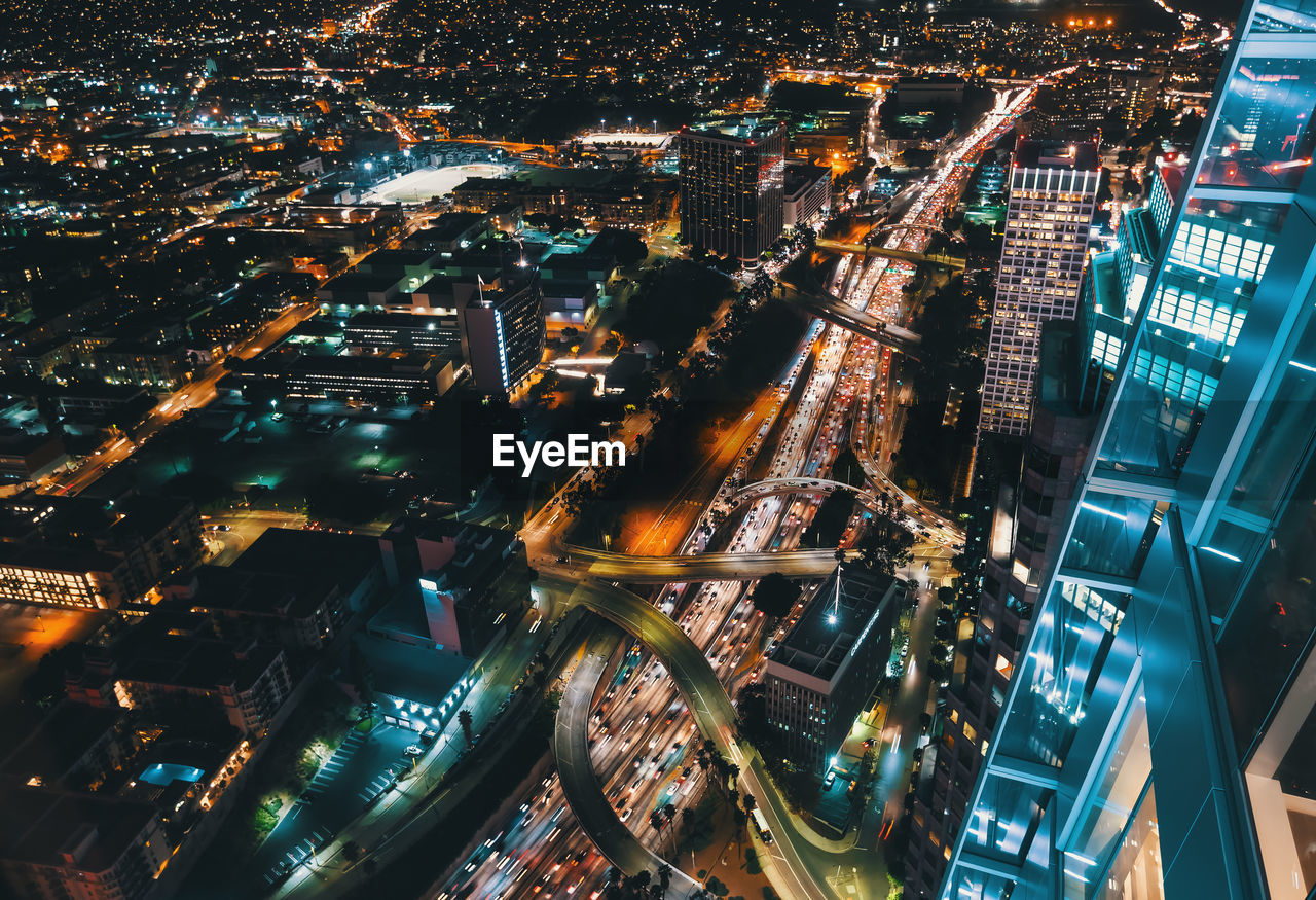 High angle view of illuminated street amidst buildings in city at night