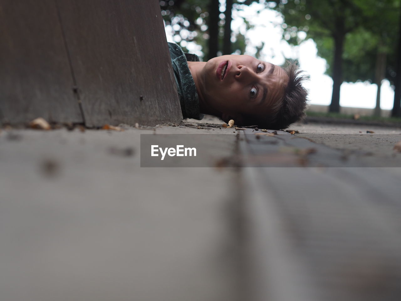 Portrait of surprised young man lying on street