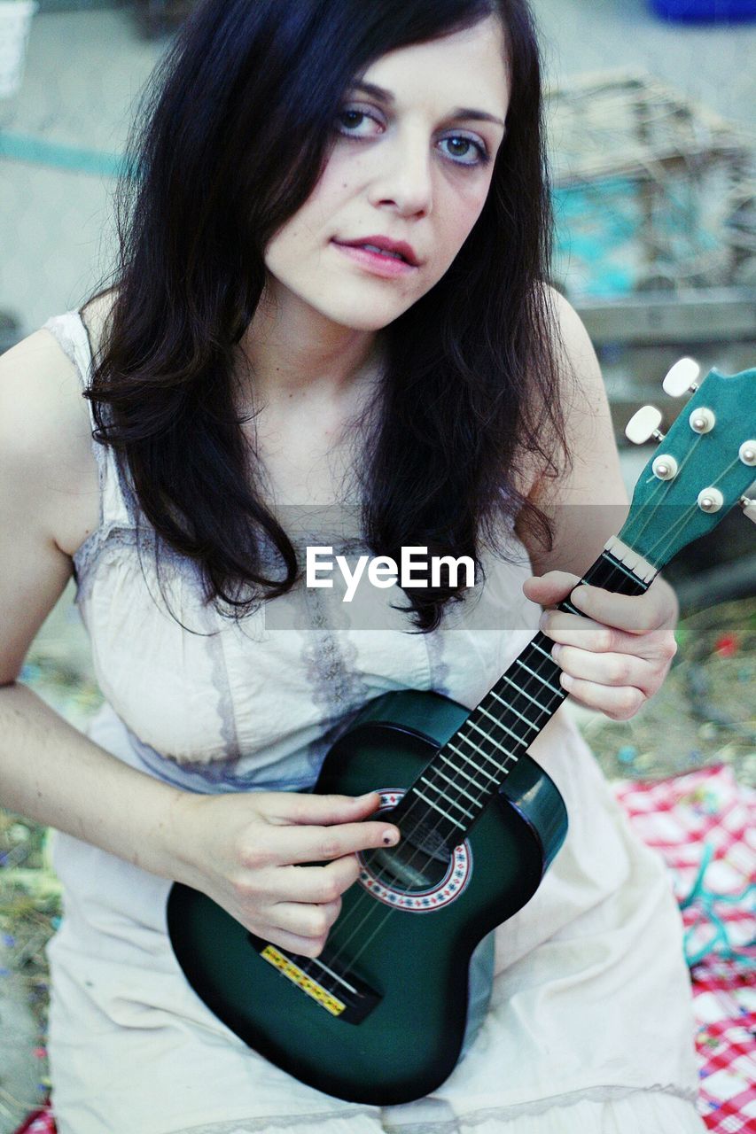 PORTRAIT OF YOUNG WOMAN PLAYING GUITAR IN MUSIC CONCERT