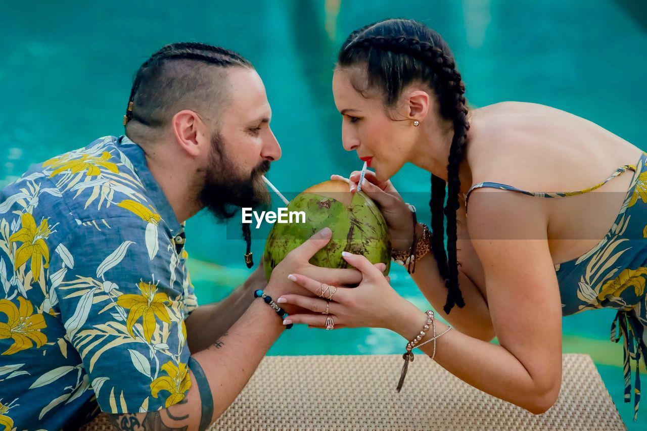 Couple drinking coconut water at poolside