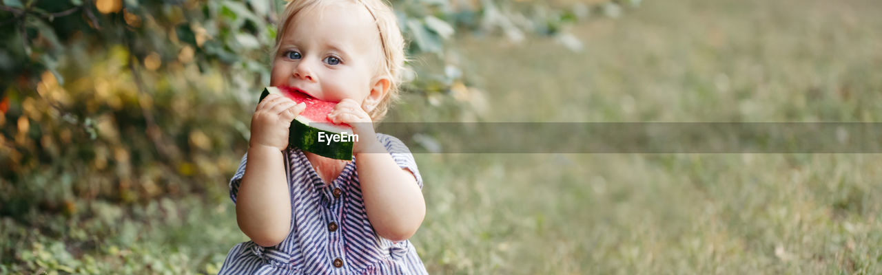 Portrait of cute girl eating watermelon outdoors