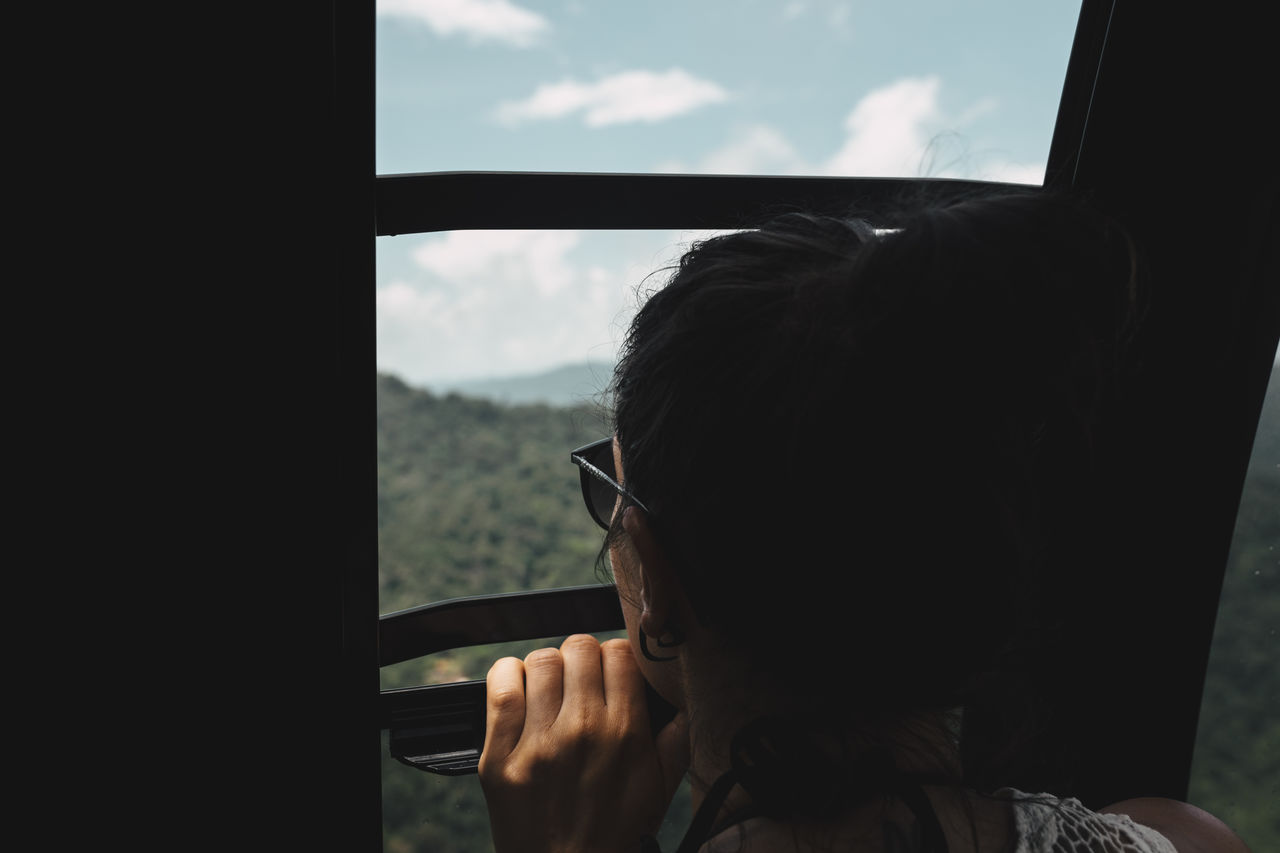 Close-up of woman looking at landscape through window