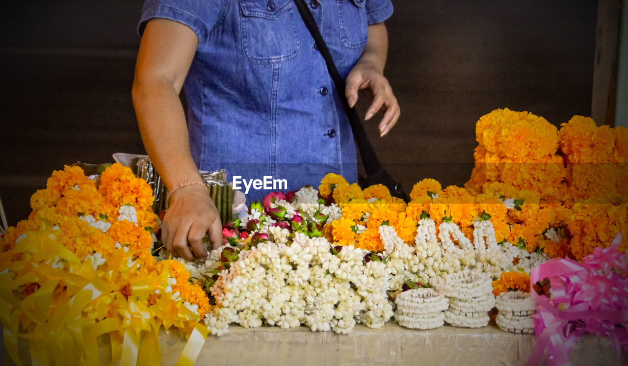 Midsection of woman with floral garland at table