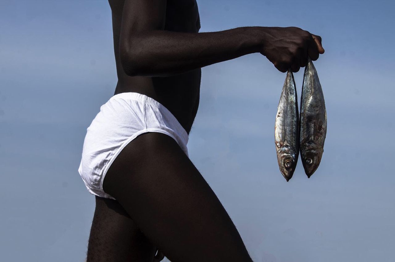 LOW ANGLE VIEW OF MAN HOLDING FISH