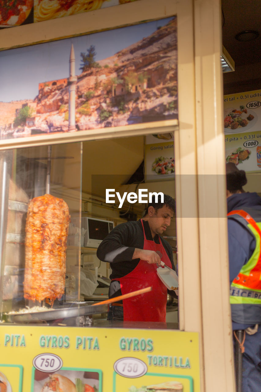 MAN LOOKING AT STORE SEEN THROUGH GLASS WINDOW OF DISPLAY AT MARKET