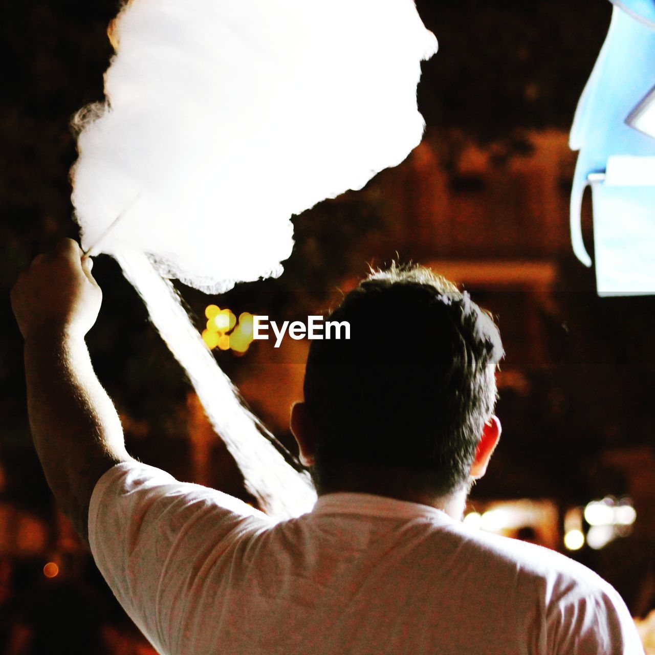 Rear view of man holding cotton candy in cafe