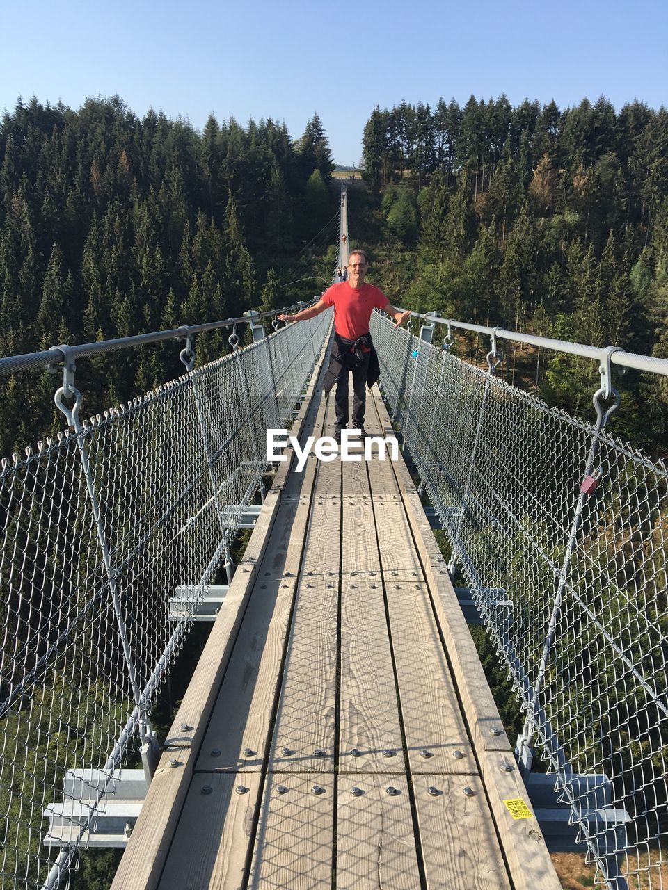 REAR VIEW OF MAN ON FOOTBRIDGE OVER BRIDGE