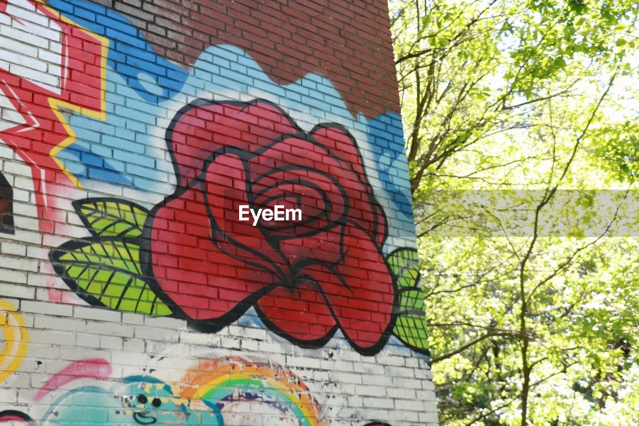 LOW ANGLE VIEW OF GRAFFITI ON WALL AGAINST TREES