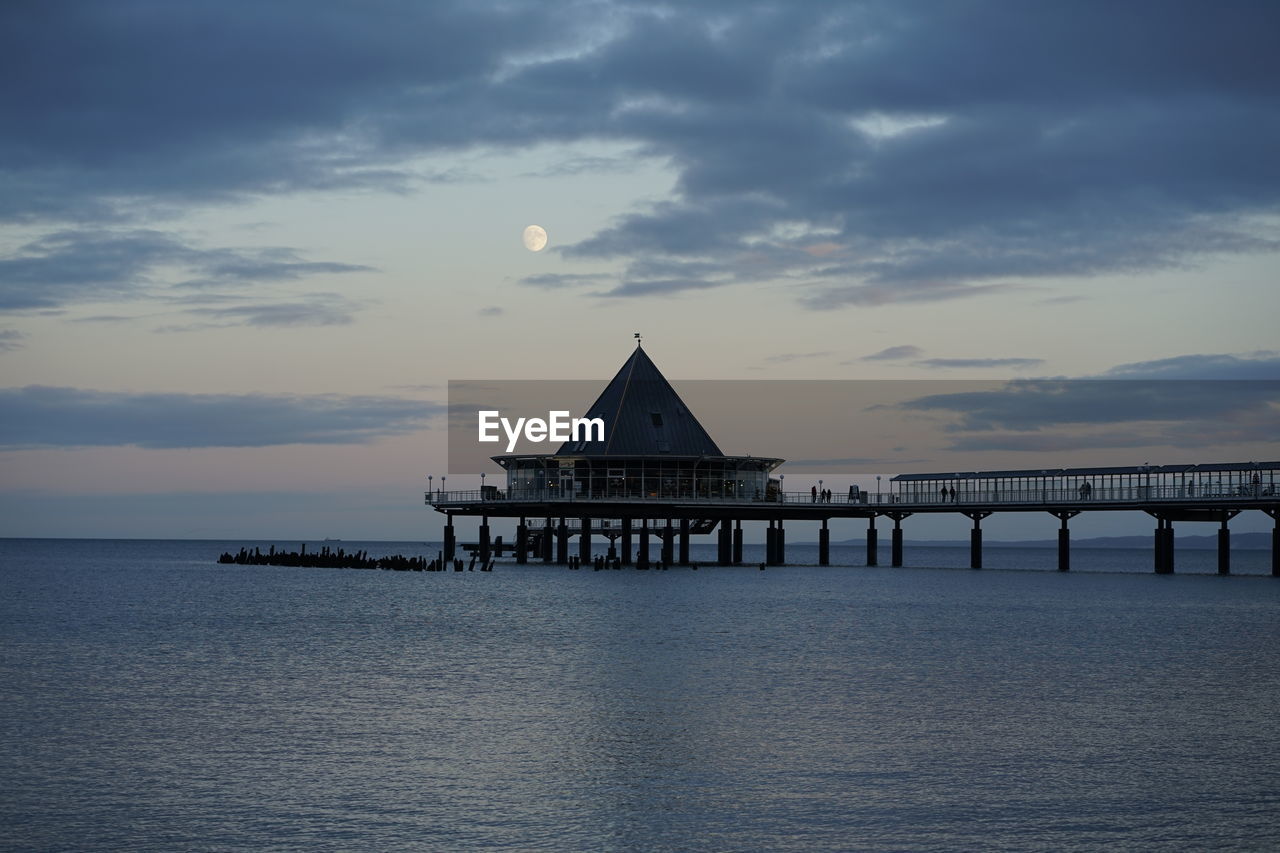 Pier over sea against sky during sunset