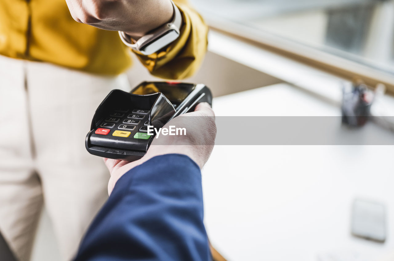 Businesswoman paying with smart watch on card reader machine