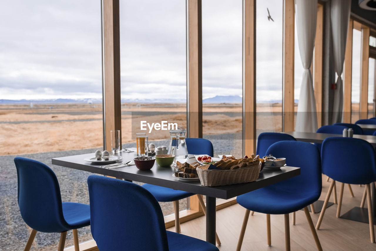 Healthy breakfast arranged on dining table by glass window at luxurious resort