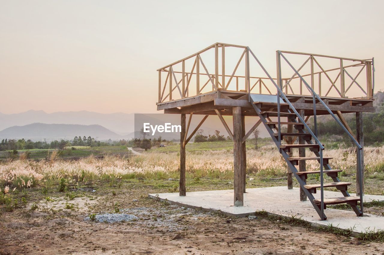 ABANDONED BRIDGE OVER FIELD AGAINST SKY