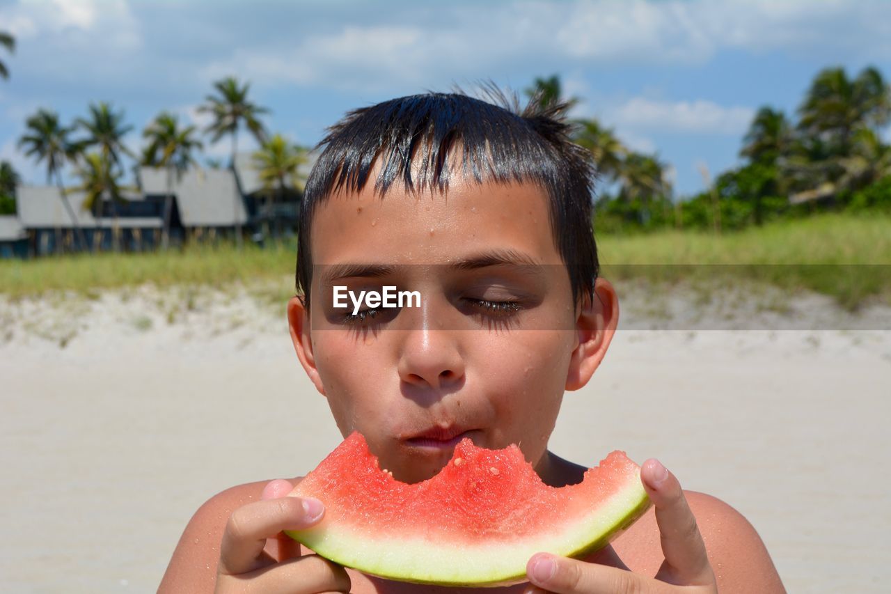 Close-up of boy eating watermelon at beach