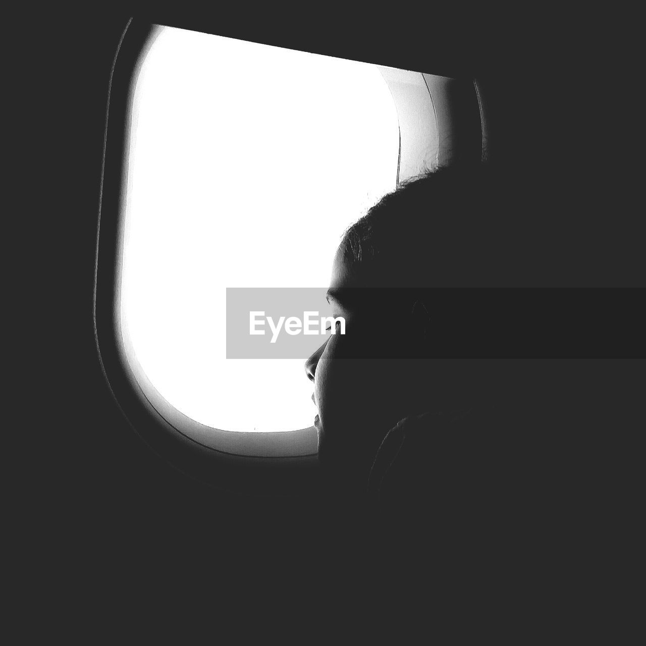 Silhouette girl looking through airplane window