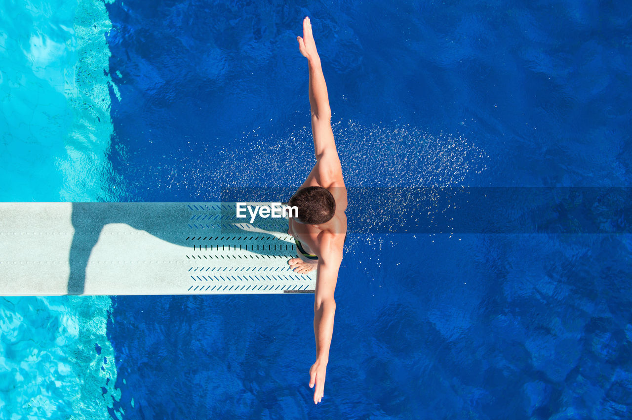 Directly above shot of man standing diving platform over pool