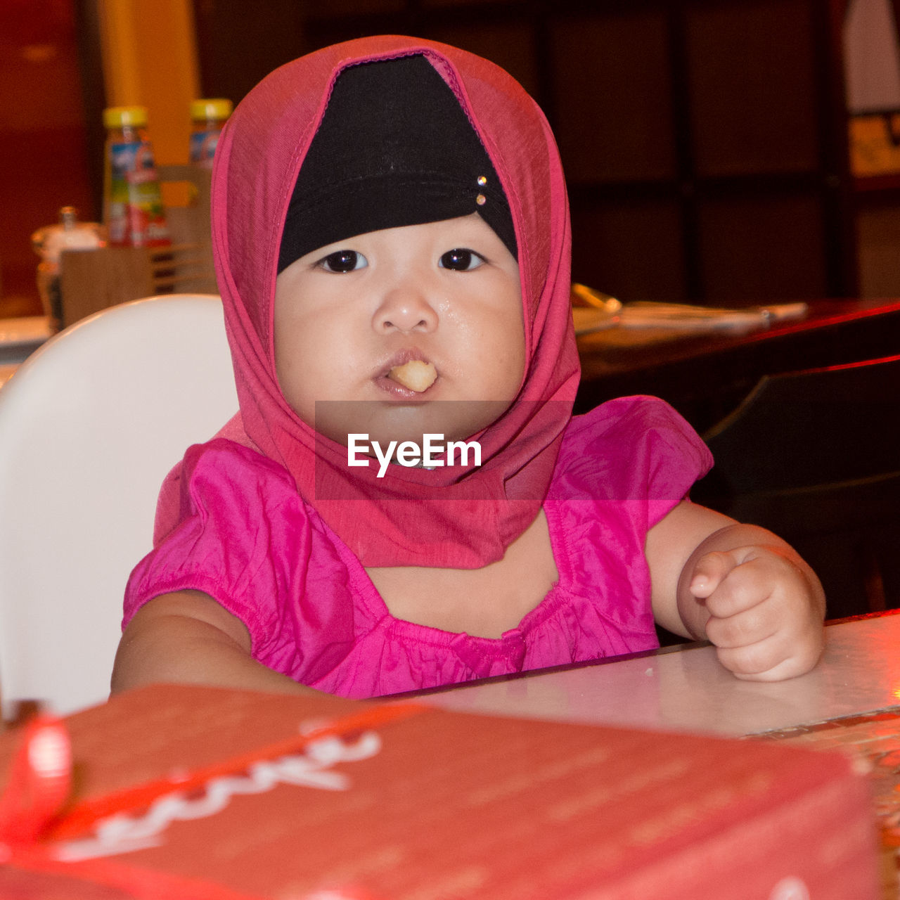 Close-up portrait of cute baby girl eating food in restaurant