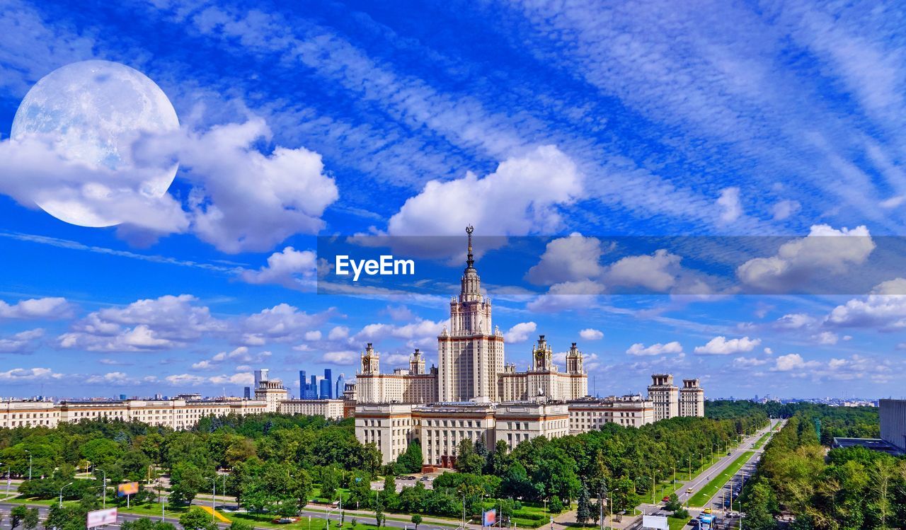 Nice blue cloudy sky with full moon over summer campus of moscow university