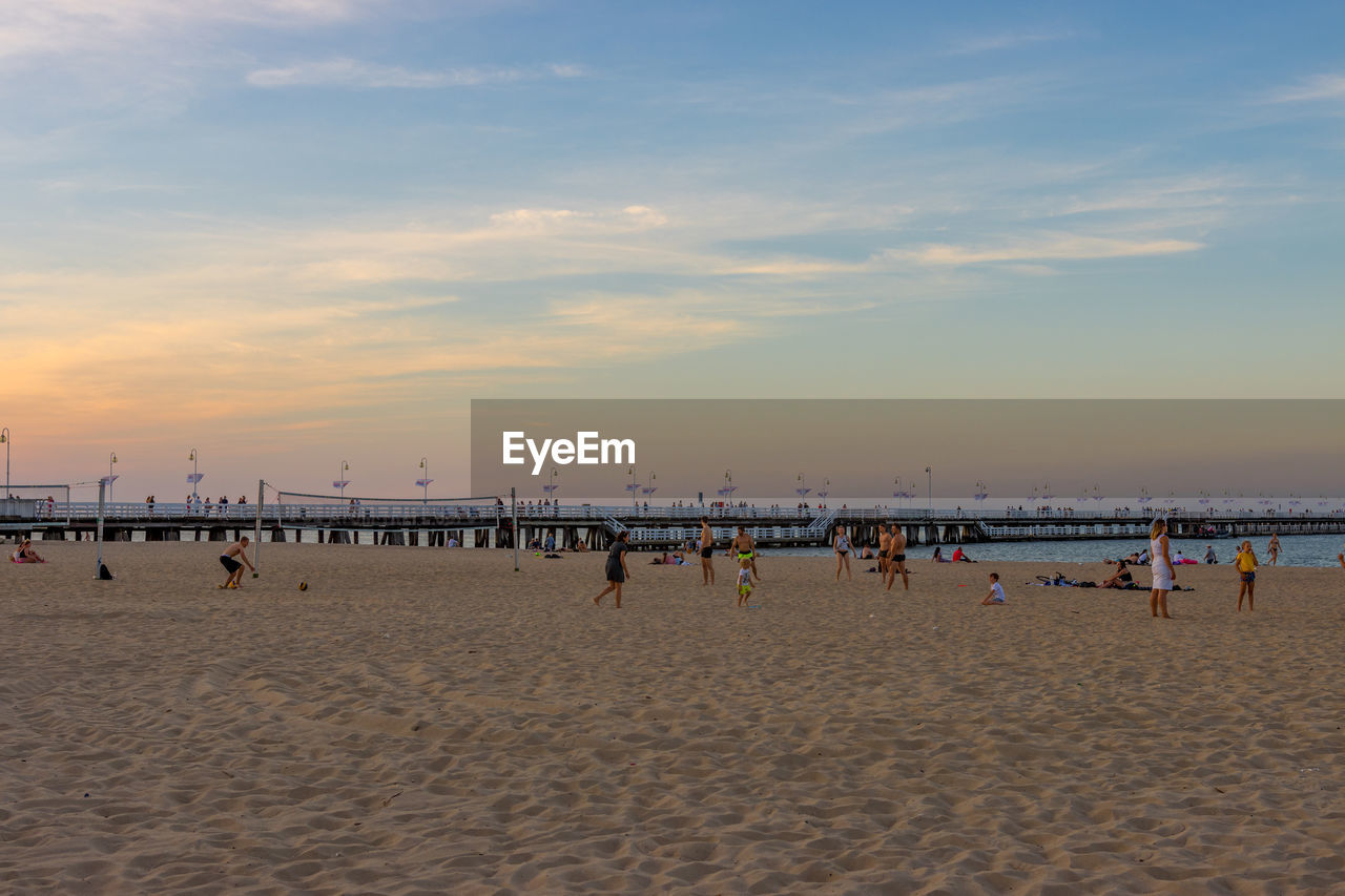 GROUP OF PEOPLE ON BEACH AGAINST SKY