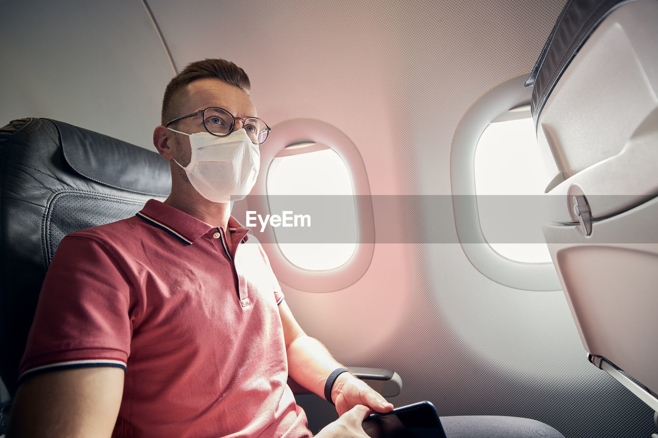 Portrait of passenger with protective face mask in airplane.