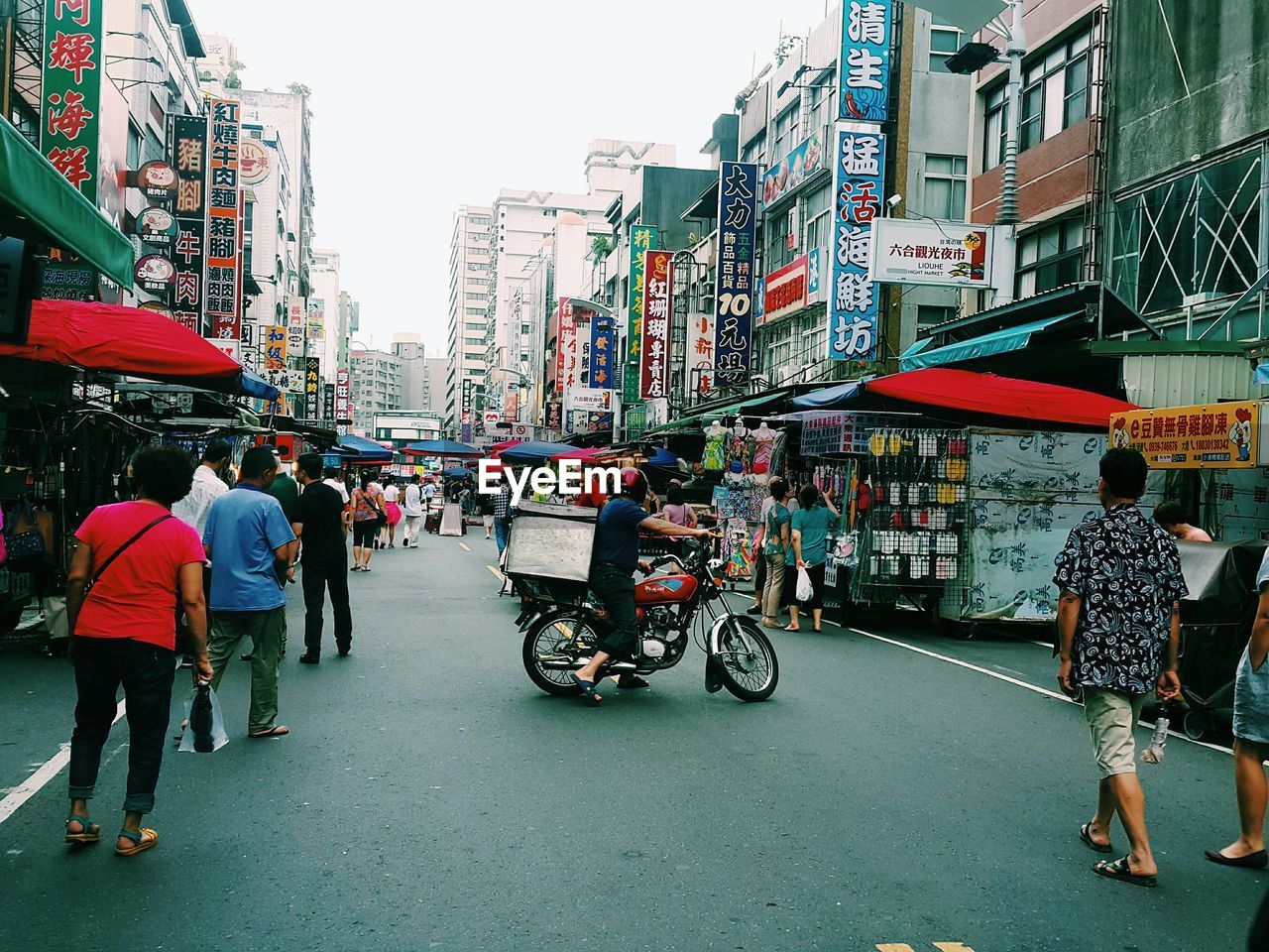 REAR VIEW OF PEOPLE WALKING ON ROAD AGAINST BUILDINGS