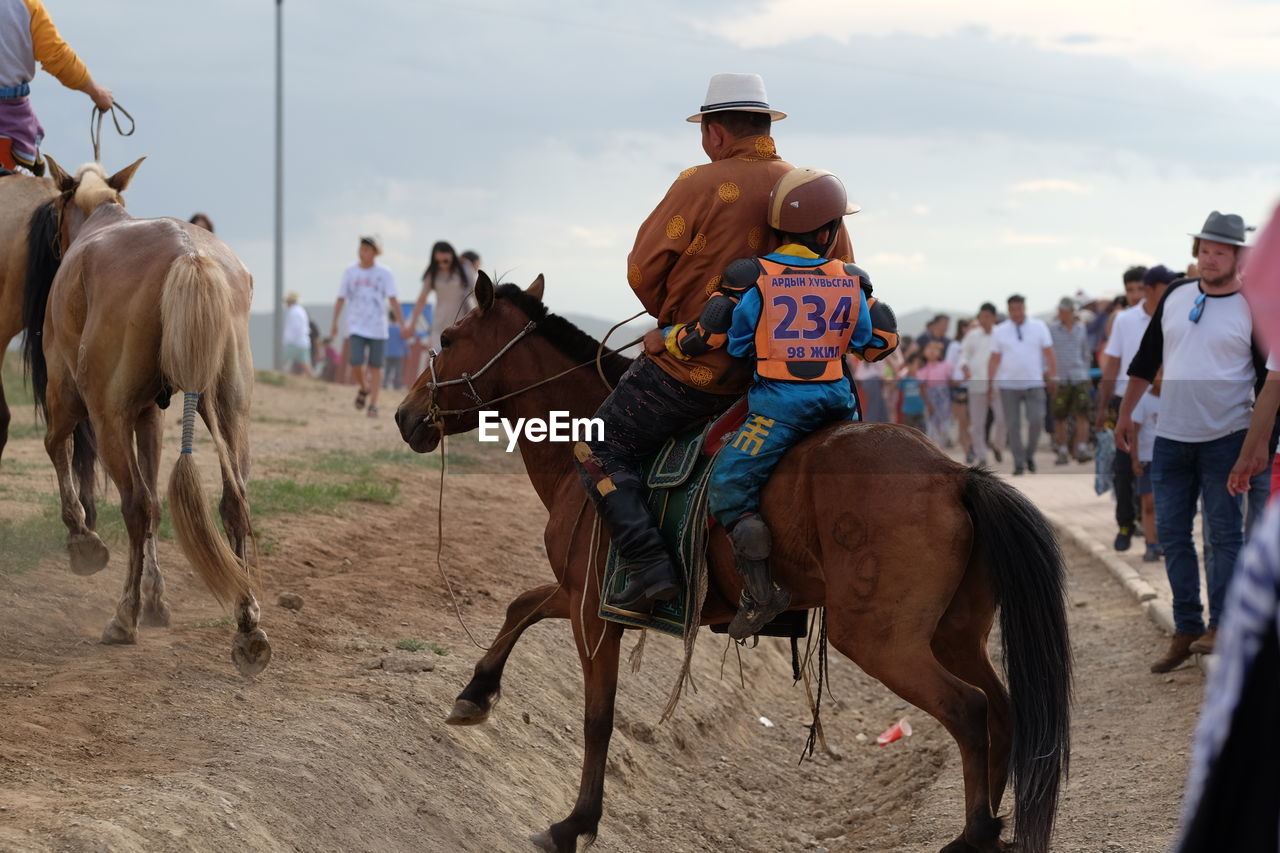 GROUP OF PEOPLE RIDING HORSES AT BEACH