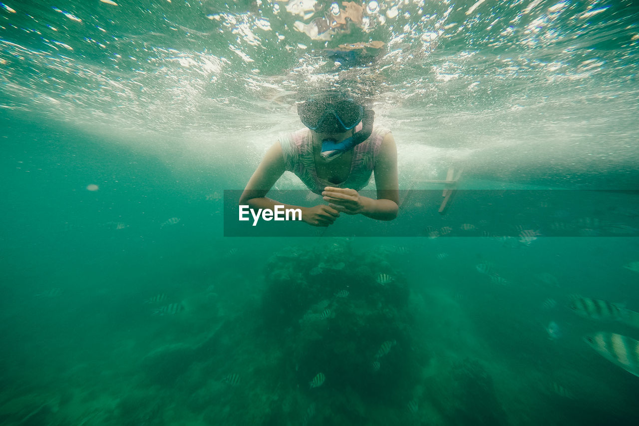 Shirtless woman swimming in sea