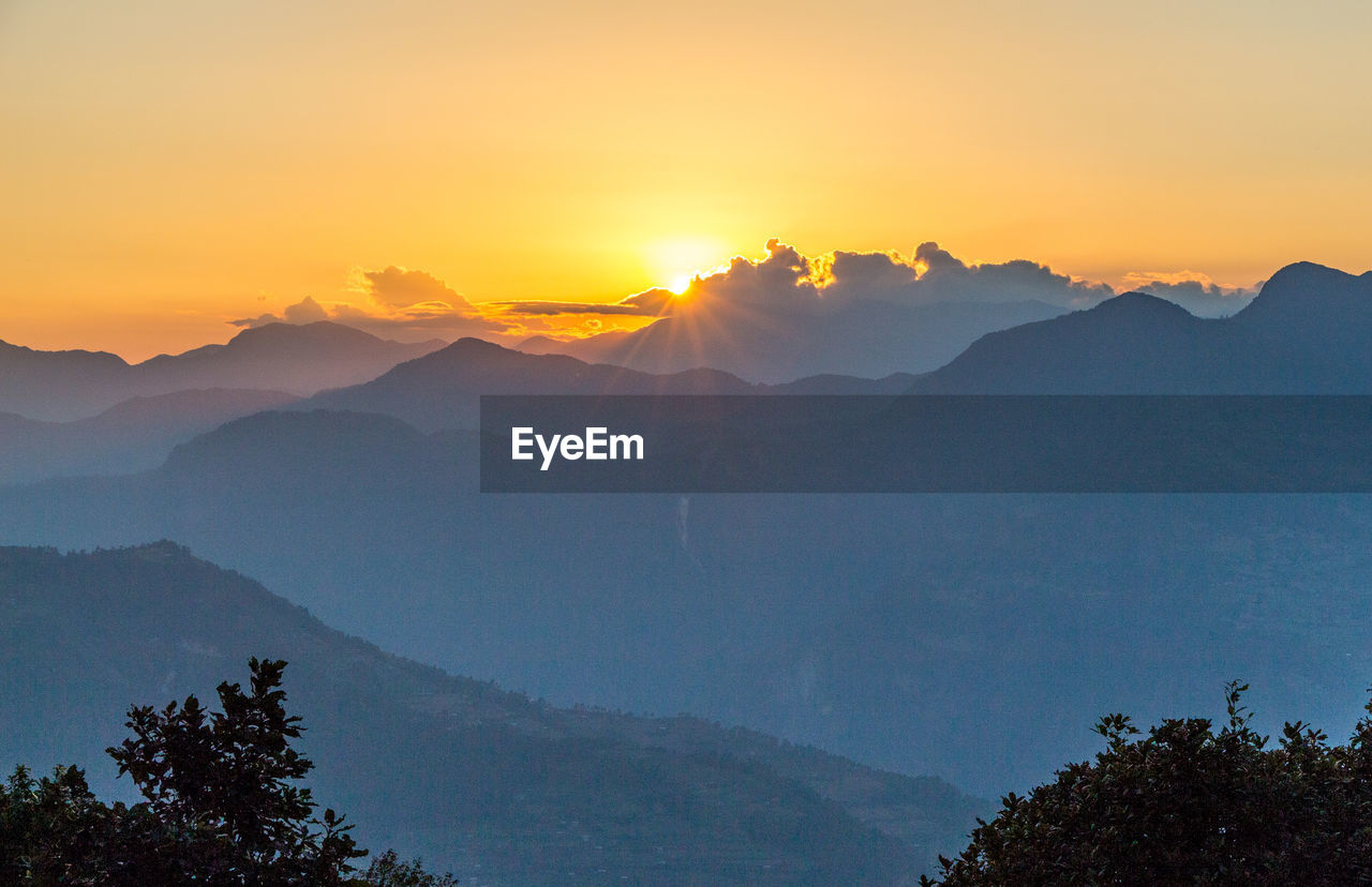 SCENIC VIEW OF SILHOUETTE MOUNTAINS AGAINST ORANGE SKY