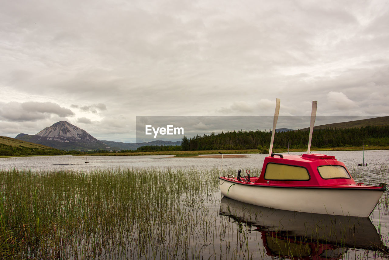 BOAT MOORED BY LAKE AGAINST SKY