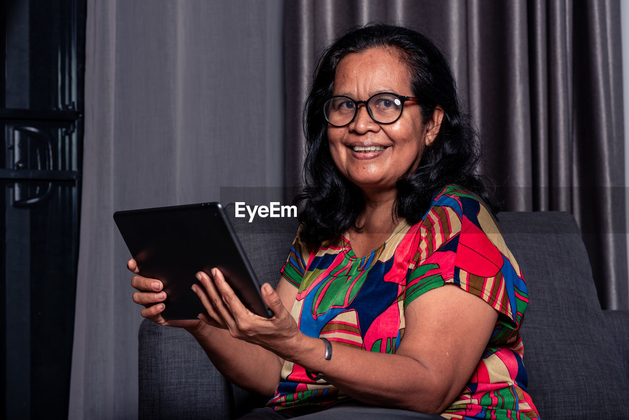 Portrait of smiling woman using digital tablet at home