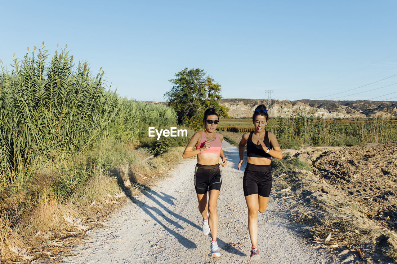 Woman with instructor running on footpath