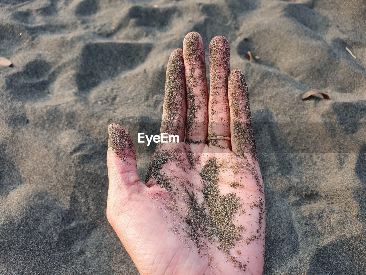 Cropped hand with sand at beach