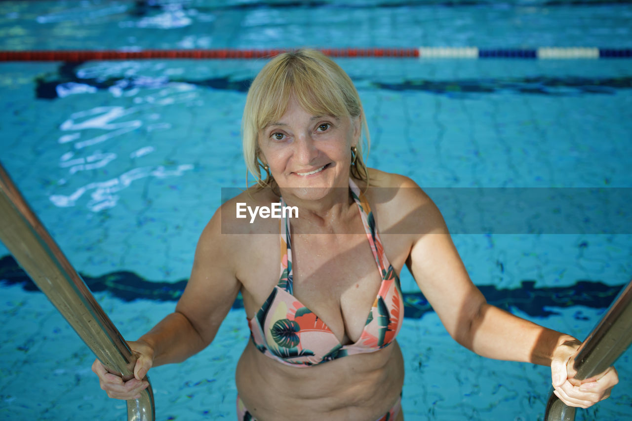 Woman in her 60s swims at public sports pool. slow aging, active lifestyle, health and vitality