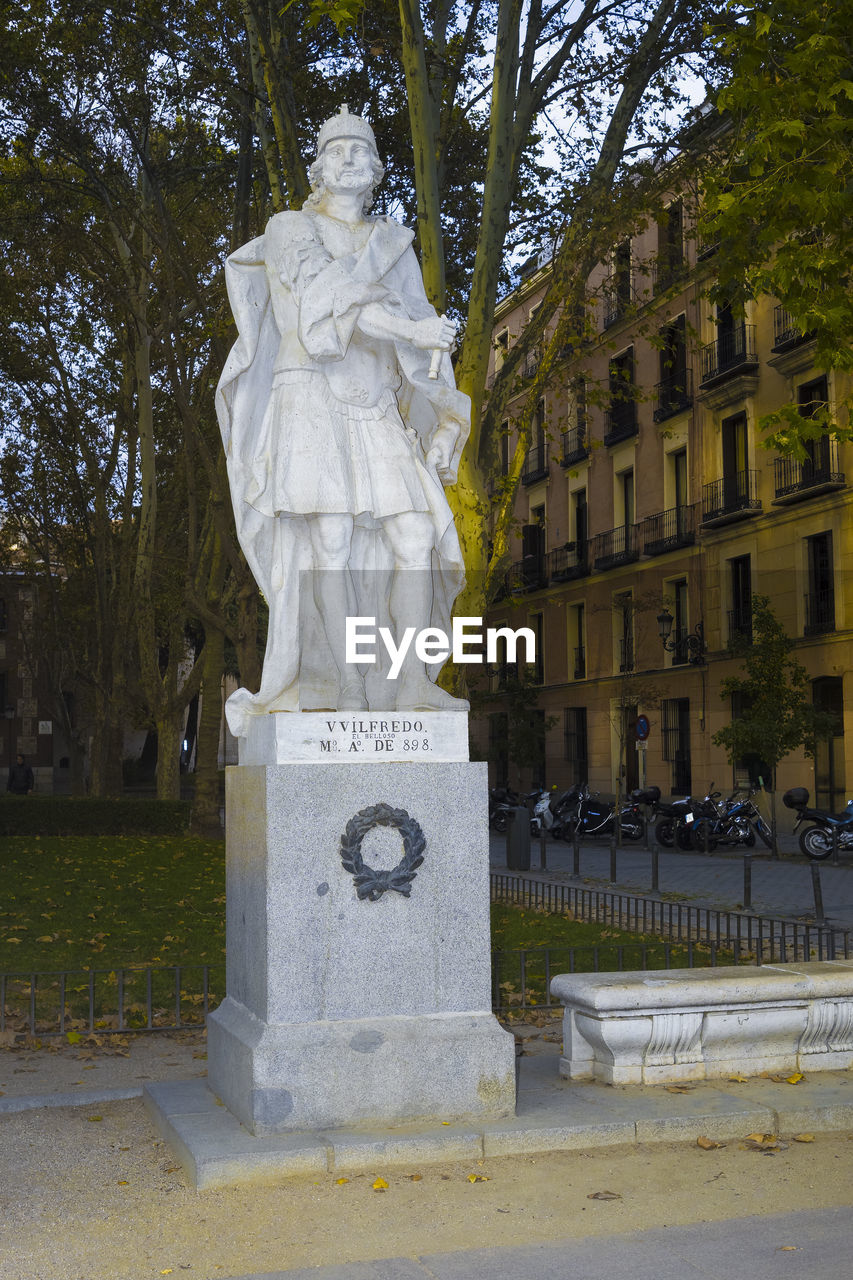 STATUE AGAINST TREES AND BUILDING