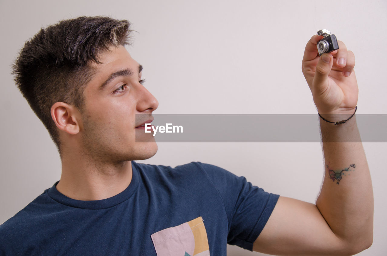 PORTRAIT OF YOUNG MAN HOLDING CAMERA