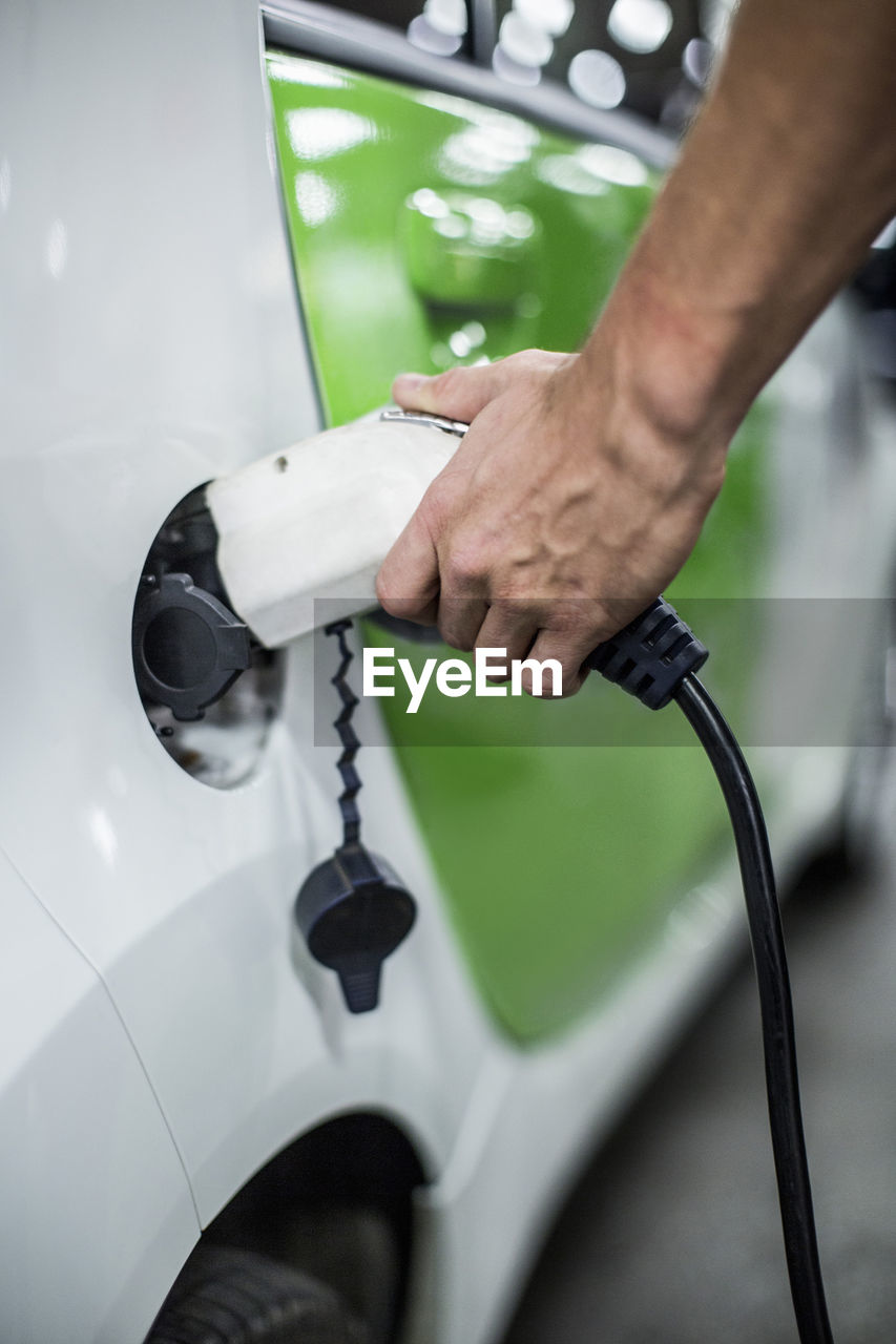 Cropped image of man charging electric car at gas station