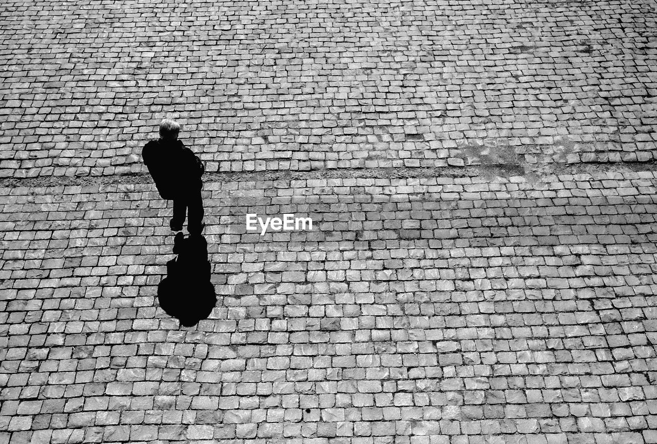 Rear view of man walking against brick wall