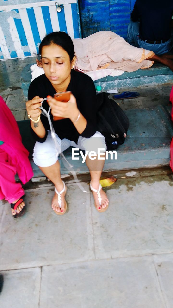 HIGH ANGLE VIEW OF WOMAN SITTING ON FLOOR