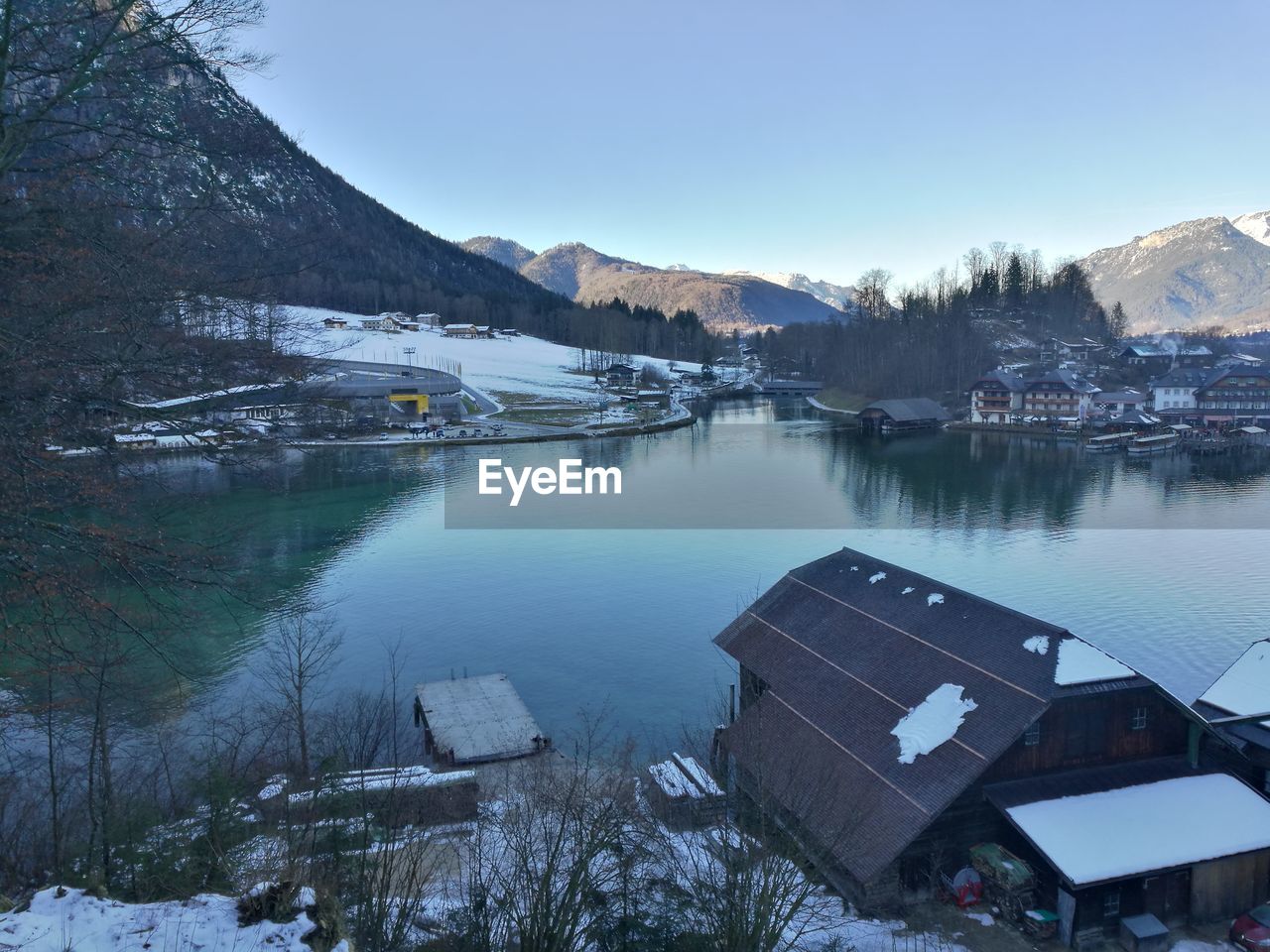 FROZEN LAKE BY HOUSES AGAINST CLEAR SKY