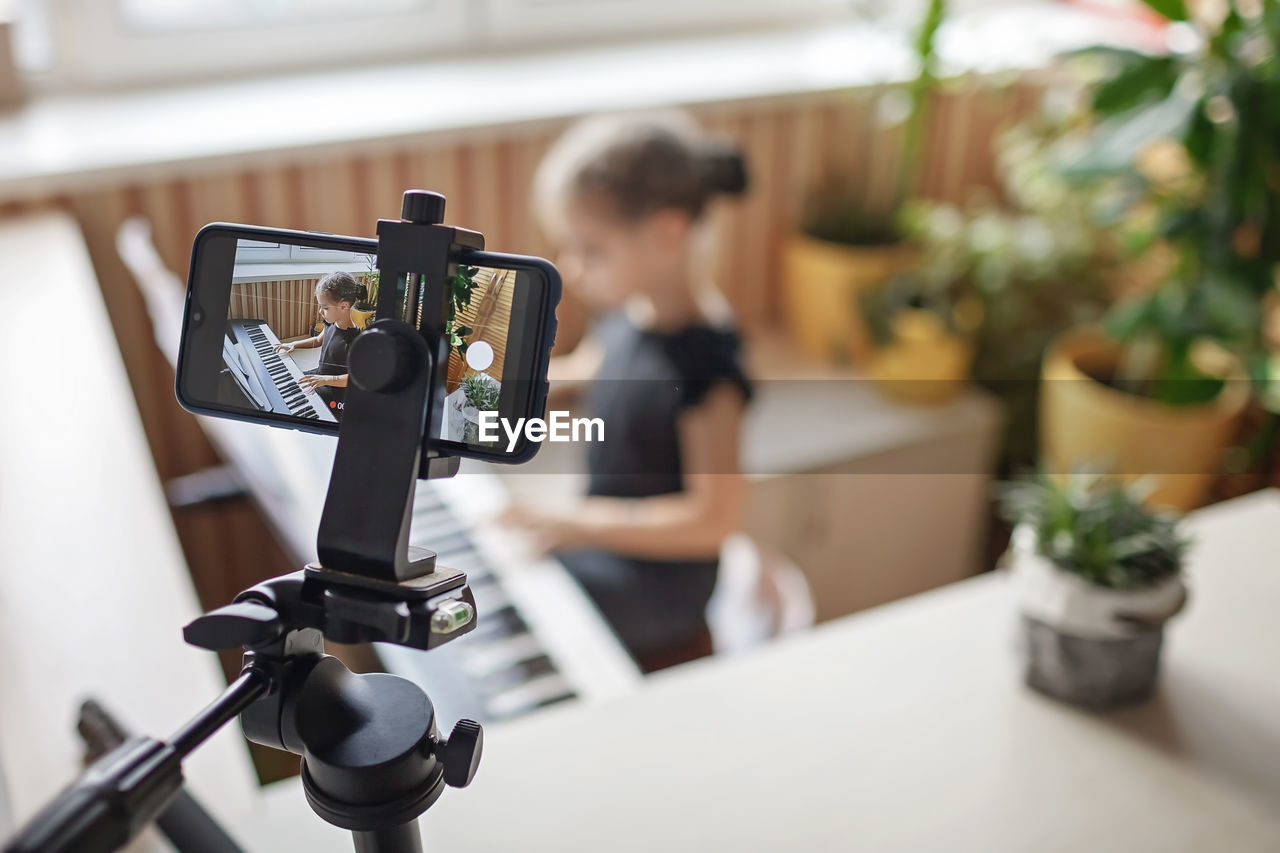 Close-up of camera recording girl playing piano