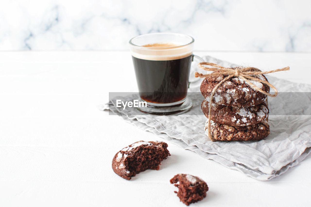 Freshly baked chocolate cookies and cup of coffee on gray napkin on wooden background.copy space.