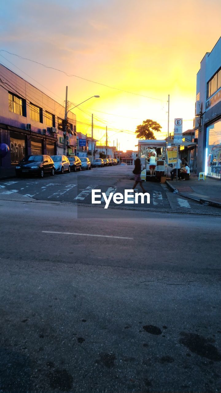 CARS ON STREET AGAINST DRAMATIC SKY DURING SUNSET